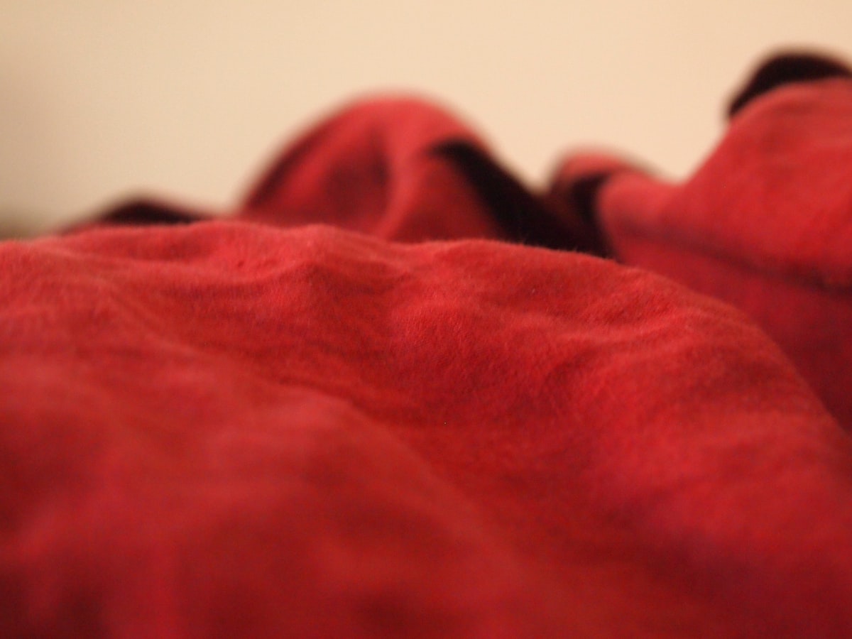 a close up of a red blanket on a bed related to The Ultimate Comfort: Bean Bag Beds with Blankets