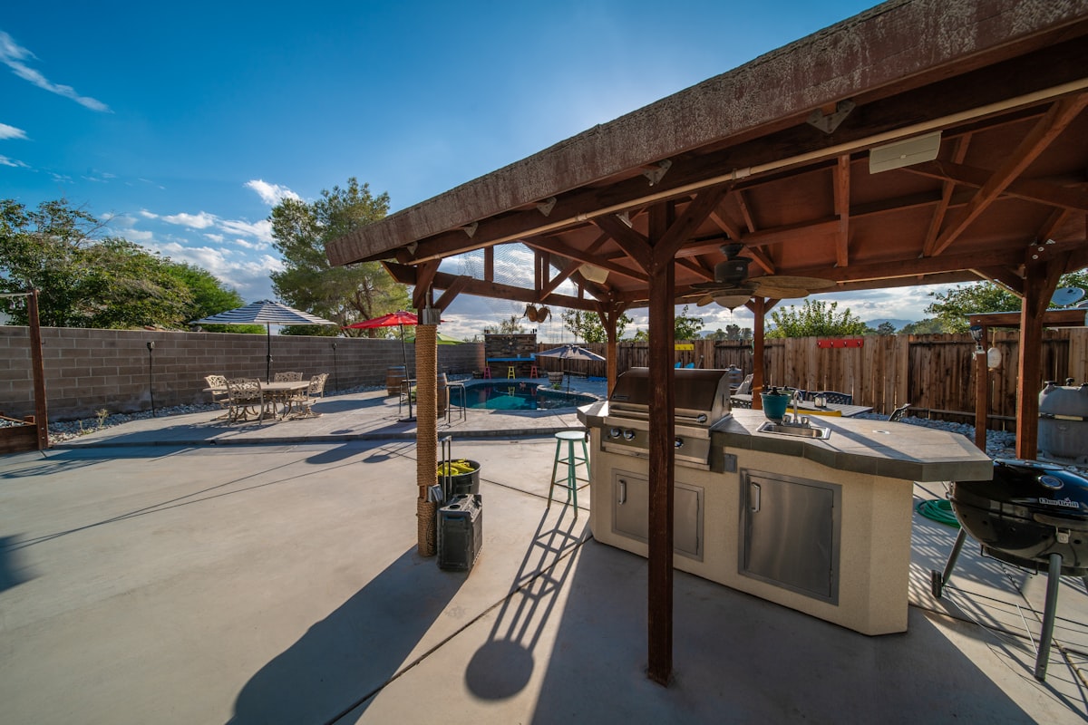a covered patio with a grill and a table related to Transform Your Backyard with a Clay Chiminea and Barbecue Grill