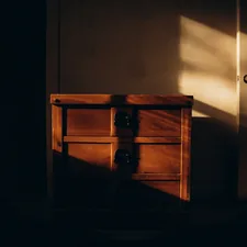 A dark room with a small chest of drawers related to The Evolution of End of Bed Dressers: A Look Back and a New Era