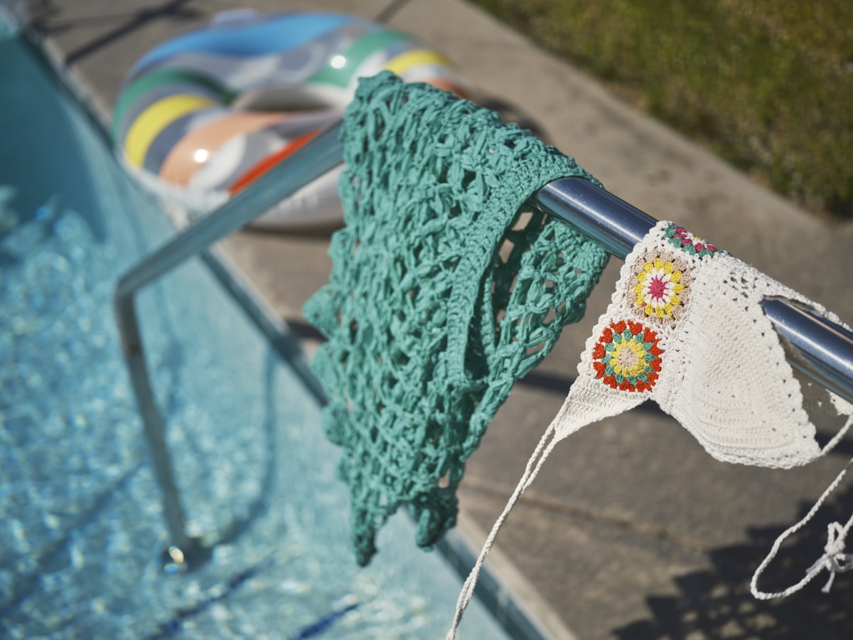 a green crocheted towel hanging on a rail next to a swimming pool related to Crochet Window Valance