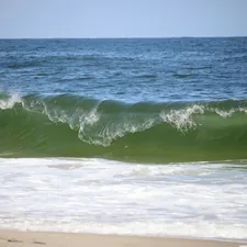 A green wave crashes on the shore. related to Discover the Charm of Rehoboth Beach Bed and Breakfasts