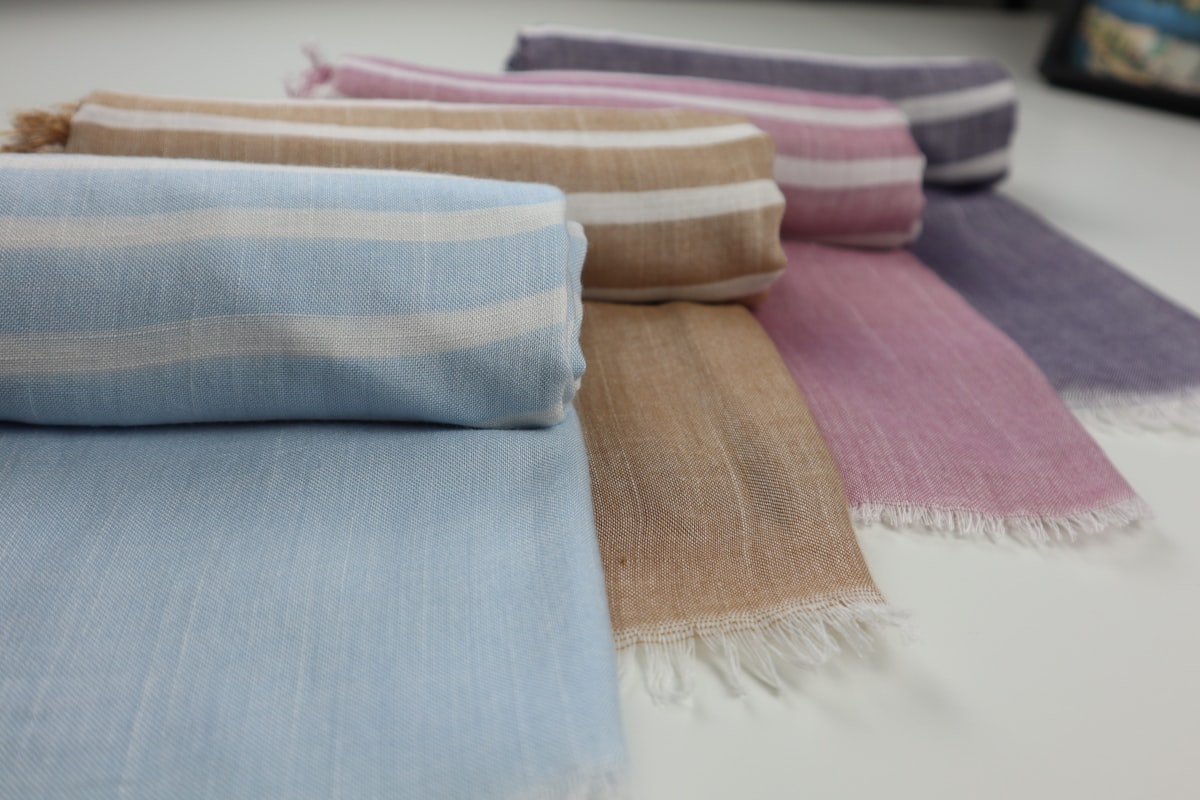 a group of different colors of blankets on a table related to How to Drape a Valance Scarf