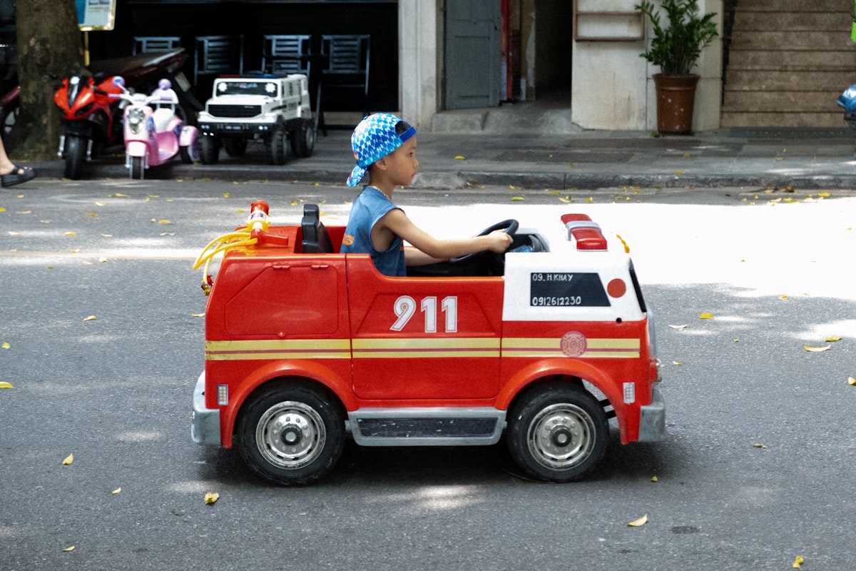A kid riding around in a toy firetruck on the streets of Hanoi. related to Transform Your Toddler's Room with a Step 2 Firetruck Bed