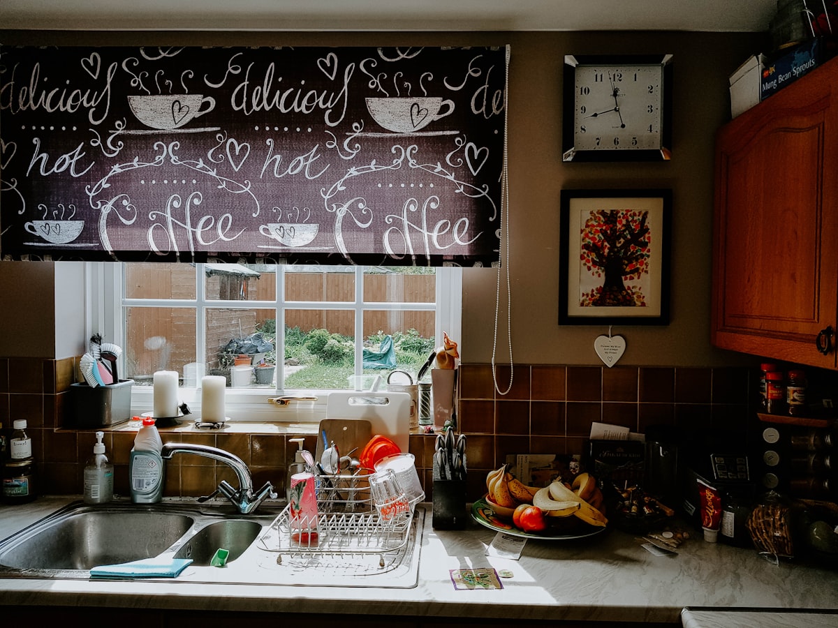 a kitchen sink under a window with a clock above it related to Kitchen Valance Patterns: Elevate Your Kitchen Decor