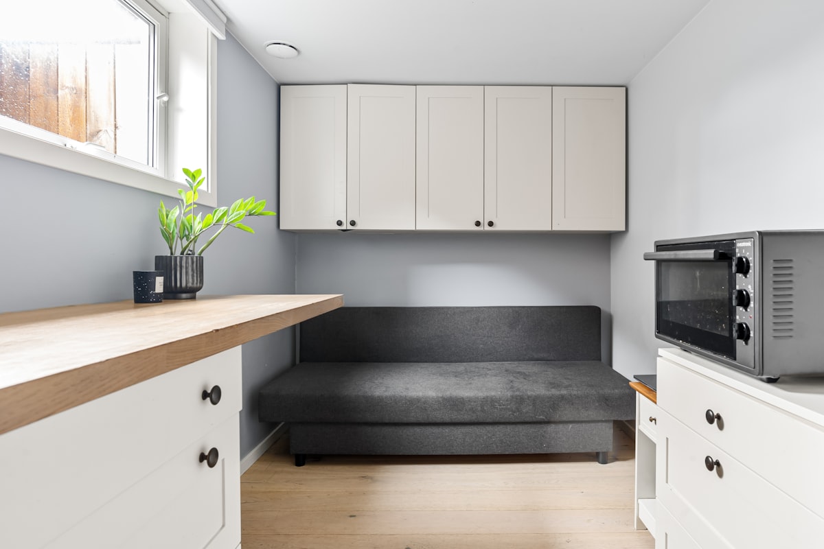 A kitchen with white cabinets and a black couch related to The Ultimate Space-Saver: Daybed with Pull Out Bed