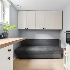 A kitchen with white cabinets and a black couch related to The Ultimate Space-Saver: Daybed with Pull Out Bed