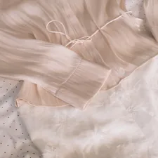 A light pink blouse with a tie waist related to The Ultimate Guide to Silk Bedding Sets