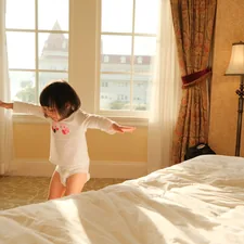 A little girl standing on a bed in a bedroom related to Snuggle Up & Stay Safe: Protecting Your Child With Bed Rails