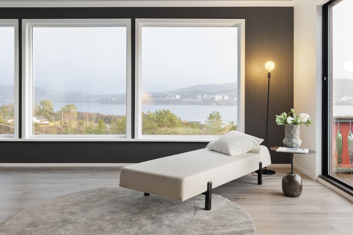 A living room with large windows and a white couch related to Sleep Soundly and Comfortably with an Adjustable Bed Frame