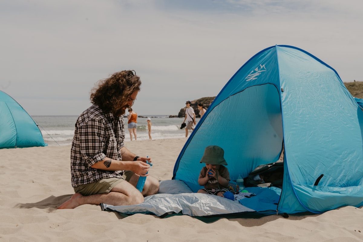 a man and a child sitting on a beach related to Ultimate Privacy and Comfort: The Privacy Pop Bed Tent Queen