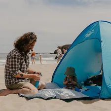 a man and a child sitting on a beach related to Ultimate Privacy and Comfort: The Privacy Pop Bed Tent Queen