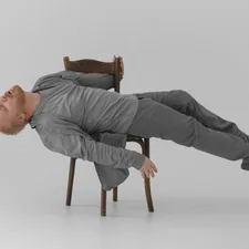 a man laying on a chair in the middle of the floor related to Space-Saving Marvels: The Ultimate Chair That Doubles as a Bed