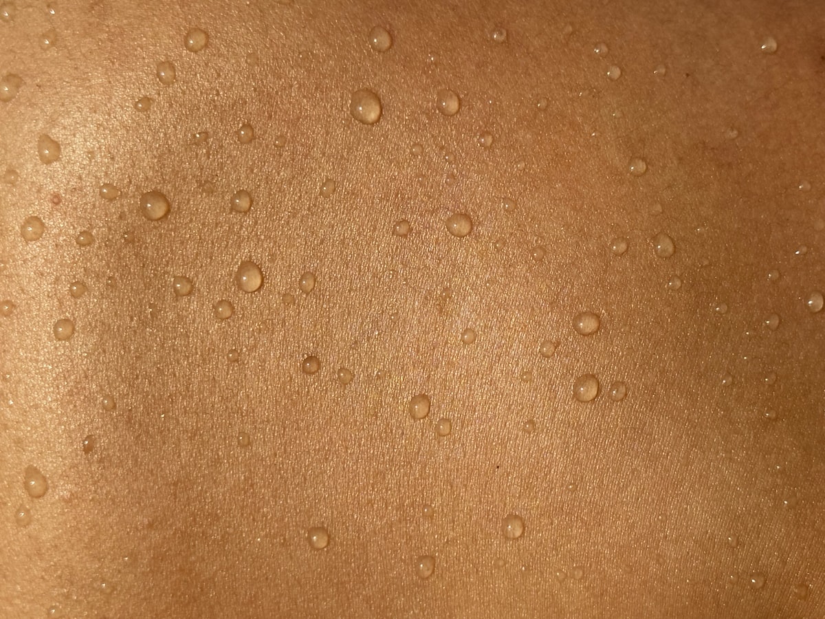 A man's back with water drops on it related to Understanding and Managing Heat Rash from Tanning Beds