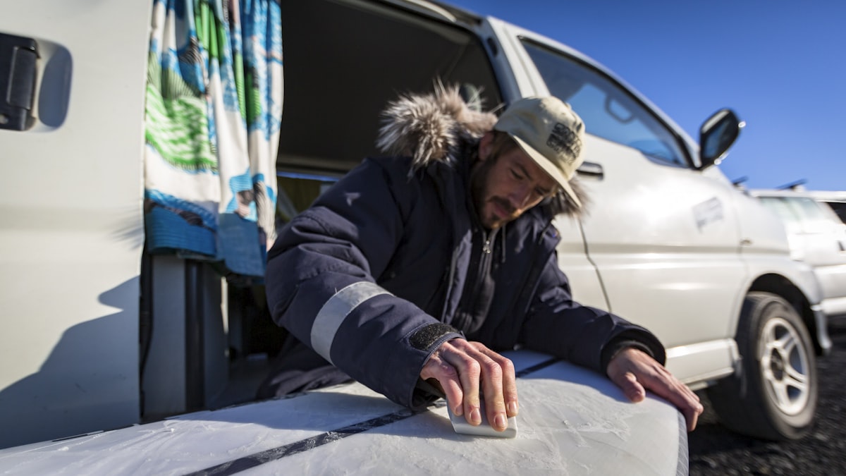 a man with a hat and a jacket on putting a surfboard into a van related to How to Effectively Patch Your Air Bed: A Step-by-Step Guide
