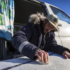 a man with a hat and a jacket on putting a surfboard into a van related to How to Effectively Patch Your Air Bed: A Step-by-Step Guide