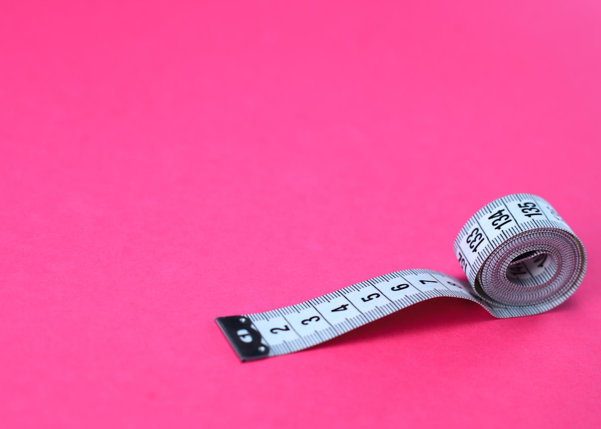 a measuring tape on a pink background related to Understanding Queen Size Bed Dimensions
