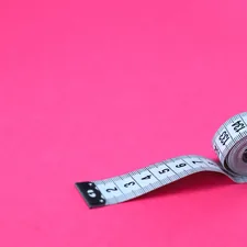 a measuring tape on a pink background related to Understanding Queen Size Bed Dimensions
