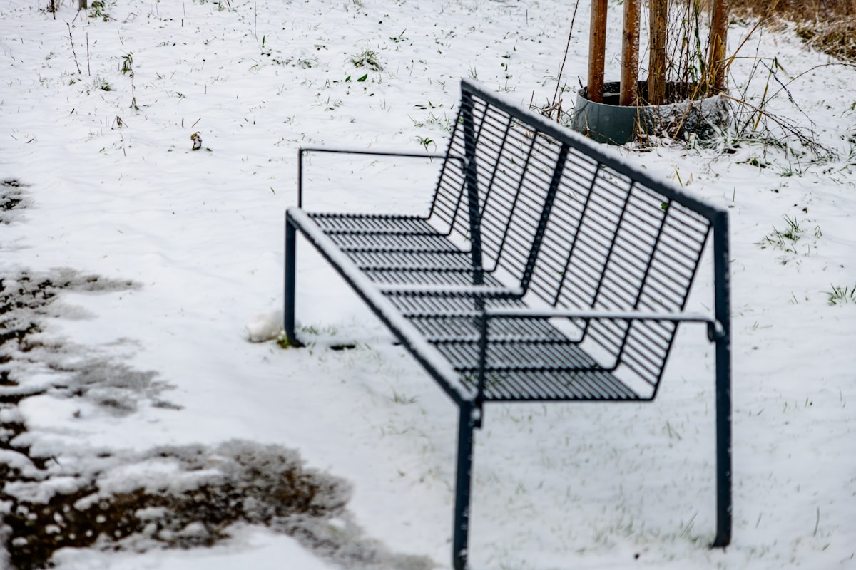A metal bench sits in the snow related to Warming Up Your Outdoor Space: The Ultimate Guide to Outdoor Clay Chimineas