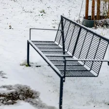 A metal bench sits in the snow related to Warming Up Your Outdoor Space: The Ultimate Guide to Outdoor Clay Chimineas