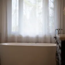 A modern bathtub with sheer curtains and a flower. related to Bathroom Curtain Valance
