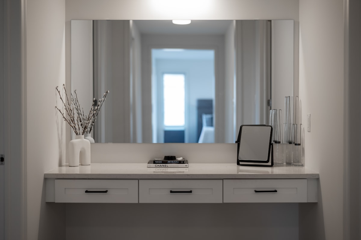 A modern vanity table with a large mirror and decor. related to Grey Entryway Table: Contemporary Style with Sophistication