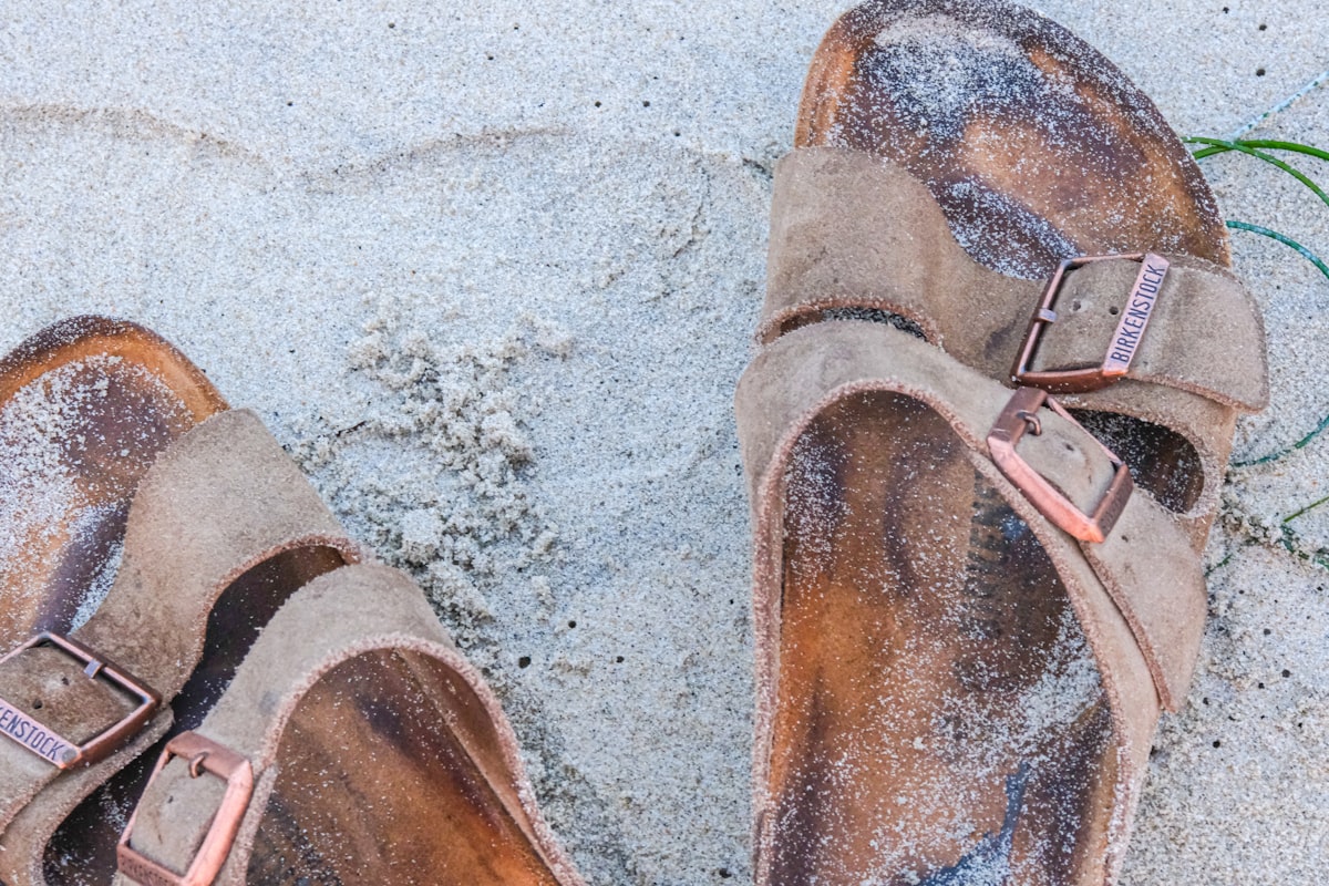 a pair of brown shoes sitting on top of a sandy beach related to The Rise of Cork Bed Sandals: Comfort Meets Sustainability