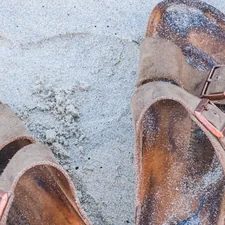 a pair of brown shoes sitting on top of a sandy beach related to The Rise of Cork Bed Sandals: Comfort Meets Sustainability