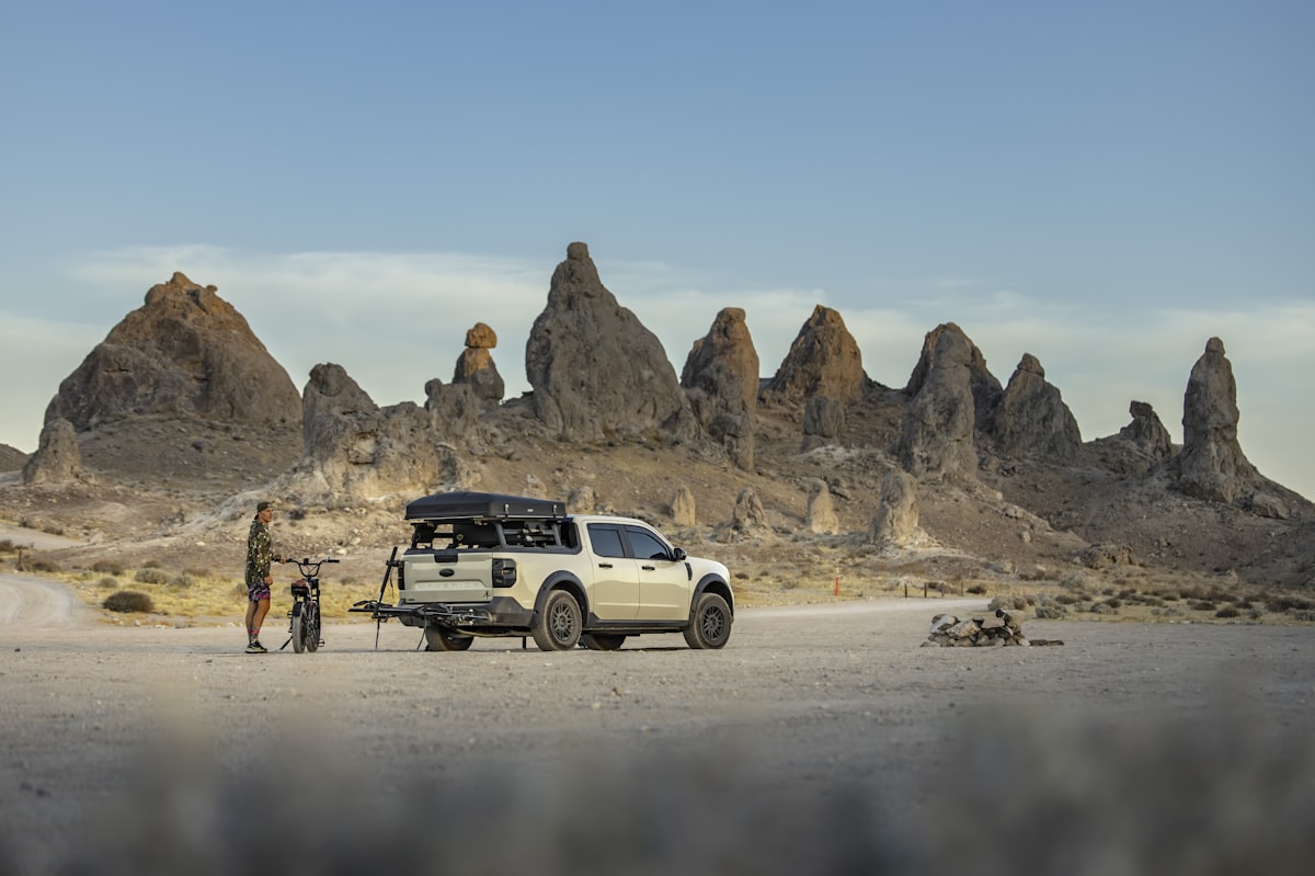 A person, dog, and truck camp among unique rock formations. related to Elevate Your Outdoor Experience with a Tacoma Bed Tent