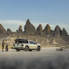 A person, dog, and truck camp among unique rock formations. related to Elevate Your Outdoor Experience with a Tacoma Bed Tent