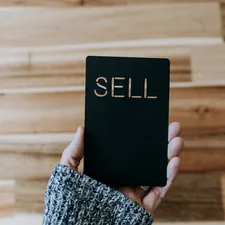 a person holding up a black book with the word sell written on it related to Ultimate Guide to Buying a Sofa Bed on Craigslist