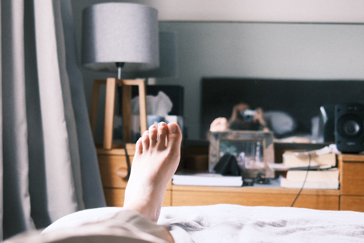 a person laying on a bed with their feet up related to Elevate Your Sleep Experience: The Ultimate Guide to Choosing the Perfect Footstool for Bed