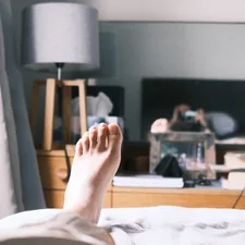 a person laying on a bed with their feet up related to Elevate Your Sleep Experience: The Ultimate Guide to Choosing the Perfect Footstool for Bed