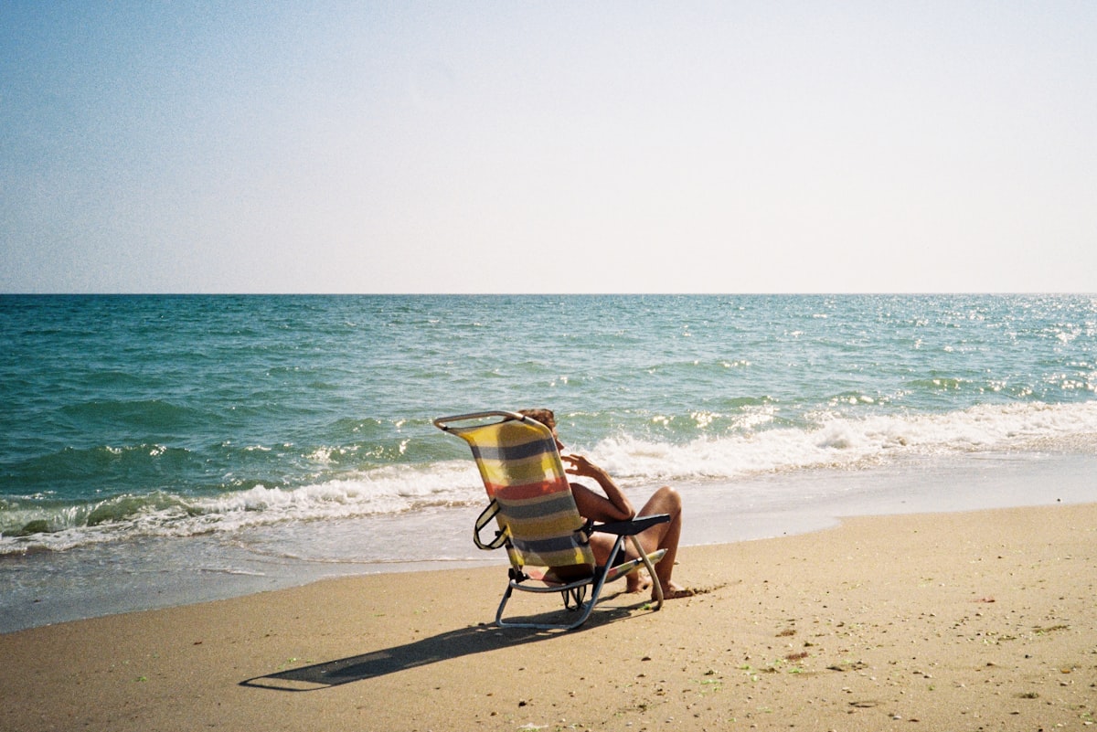 a person sitting in a chair on a beach related to Discover the Comfort of Holiday Inn Bedding