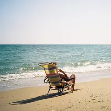 a person sitting in a chair on a beach related to Discover the Comfort of Holiday Inn Bedding