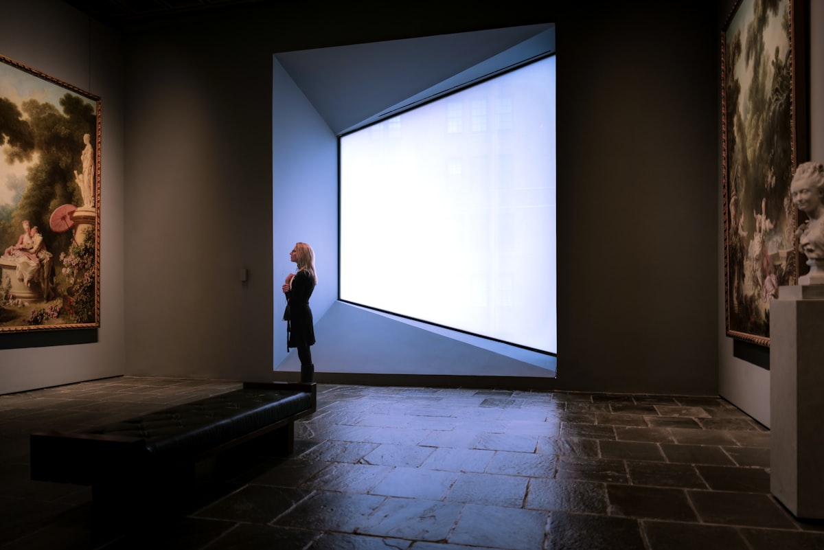 a person standing in a room with paintings on the wall related to The Art of Window Valances: Exploring Cornice Window Valance Options
