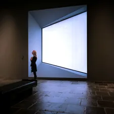 a person standing in a room with paintings on the wall related to The Art of Window Valances: Exploring Cornice Window Valance Options