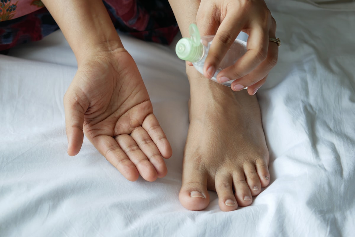 a person with a bottle on their foot on a bed related to The Painful Reality of Infected Nail Beds