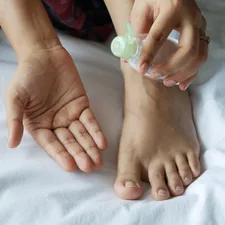 a person with a bottle on their foot on a bed related to The Painful Reality of Infected Nail Beds