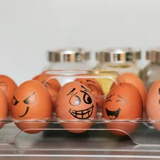 A photograph (wallpaper, picture) of eggs with different emotions against a background of blurred spices and a smooth gray wall.  Whole painted eggs in the kitchen, expressing a spectrum of emotions from sadness to joy or madness. Eggs with smile and crazy face. related to How Many Eggs Do Bed Bugs Lay?