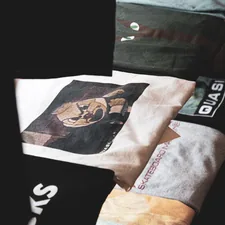 a pile of shirts sitting on top of a bed related to Level Up Your Lounge: Swag Curtains with Valance