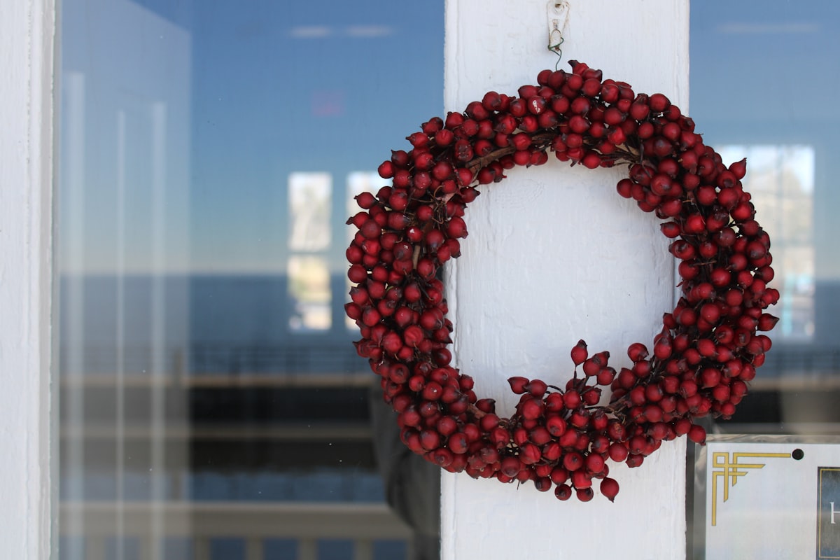 a red berry wreath hangs on a white door related to Deck the Entryway: Creative and Festive Christmas Decor Ideas