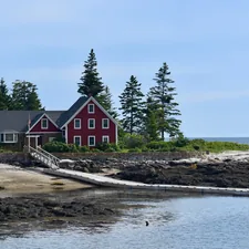 a red house on a rocky shore related to Discover the Charm of Bed and Breakfast Maine