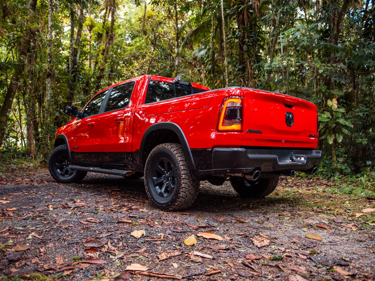 A red truck parks amidst a lush forest. related to Top Bed Covers for Ram 1500: Ultimate Guide for Style and Protection