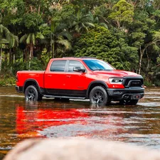 A red truck wades through shallow water. related to Top Bed Covers for Ram 1500: Ultimate Guide for Style and Protection