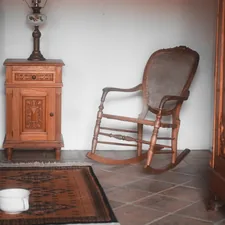 a rocking chair in a room with a rug on the floor related to Rocking Your Way to Relaxation: The Benefits of Rocking Beds for Adults