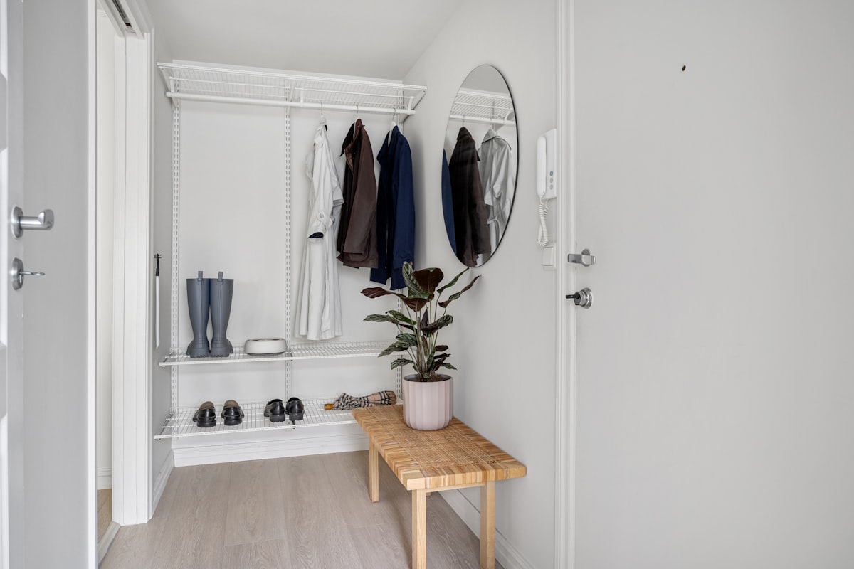 A room with a bench, coat rack, and mirror related to Elegant Entryway Solution: Mirror with Hooks and Shelf