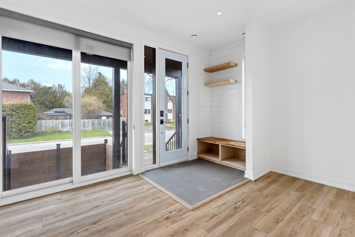 a room with a wood floor and a glass door with a rug and a wood floor with a related to Elevate Your Entryway: The Ultimate Guide to Benches with Storage and Hooks
