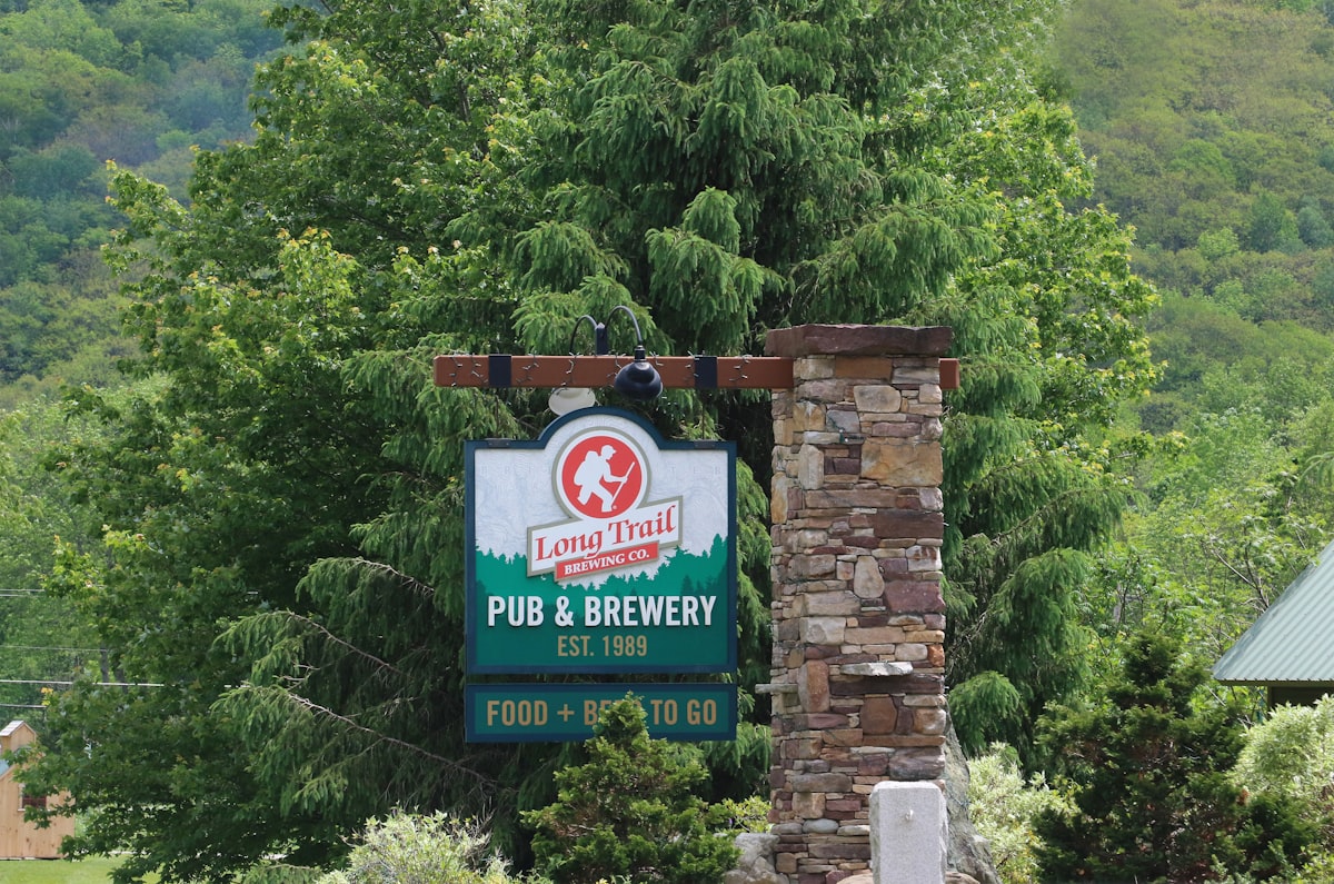 a sign for a pub and brewery in a wooded area related to Discover the Charm of Vermont's Cozy Bed and Breakfasts