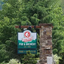 a sign for a pub and brewery in a wooded area related to Discover the Charm of Vermont's Cozy Bed and Breakfasts