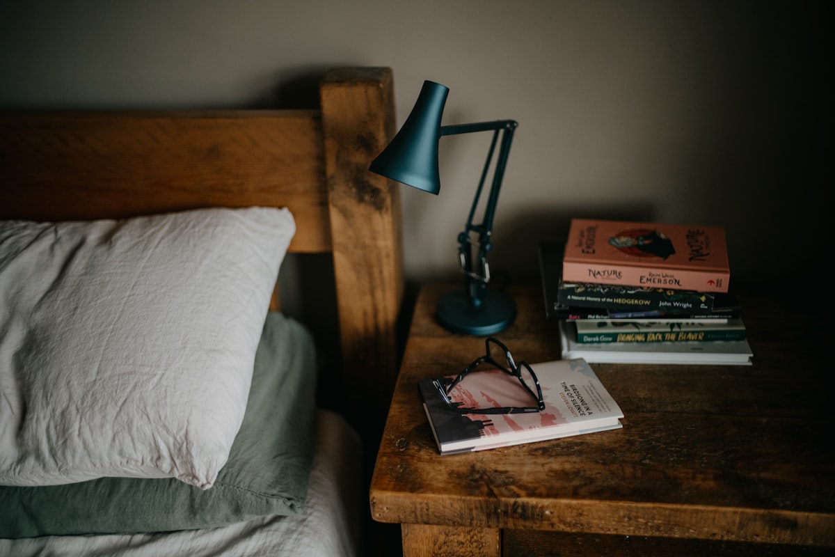 a stack of books sitting on top of a bed next to a lamp related to The Ultimate Guide to Choosing the Perfect Bed Size
